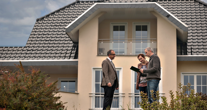 Couple standing outside a house talking to real estate agent